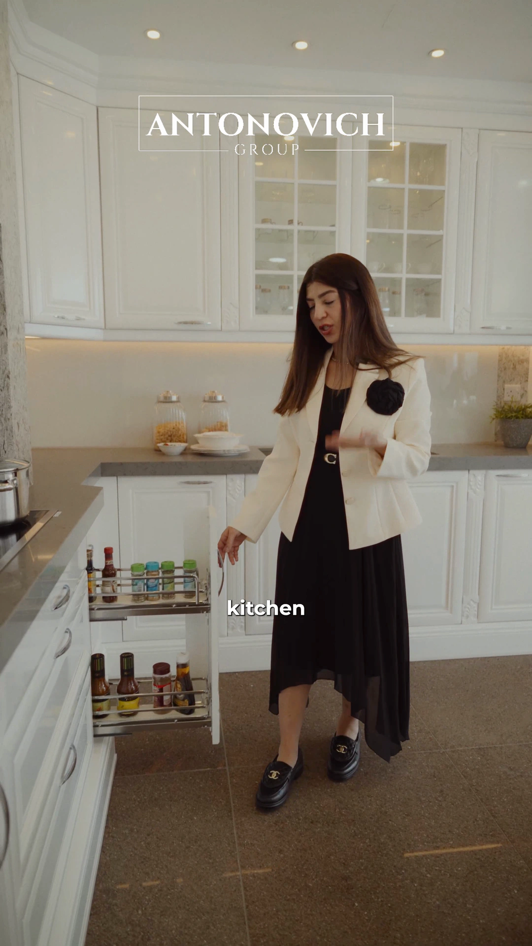 Project manager in a white jacket showing a pull-out spice rack in a classic white kitchen