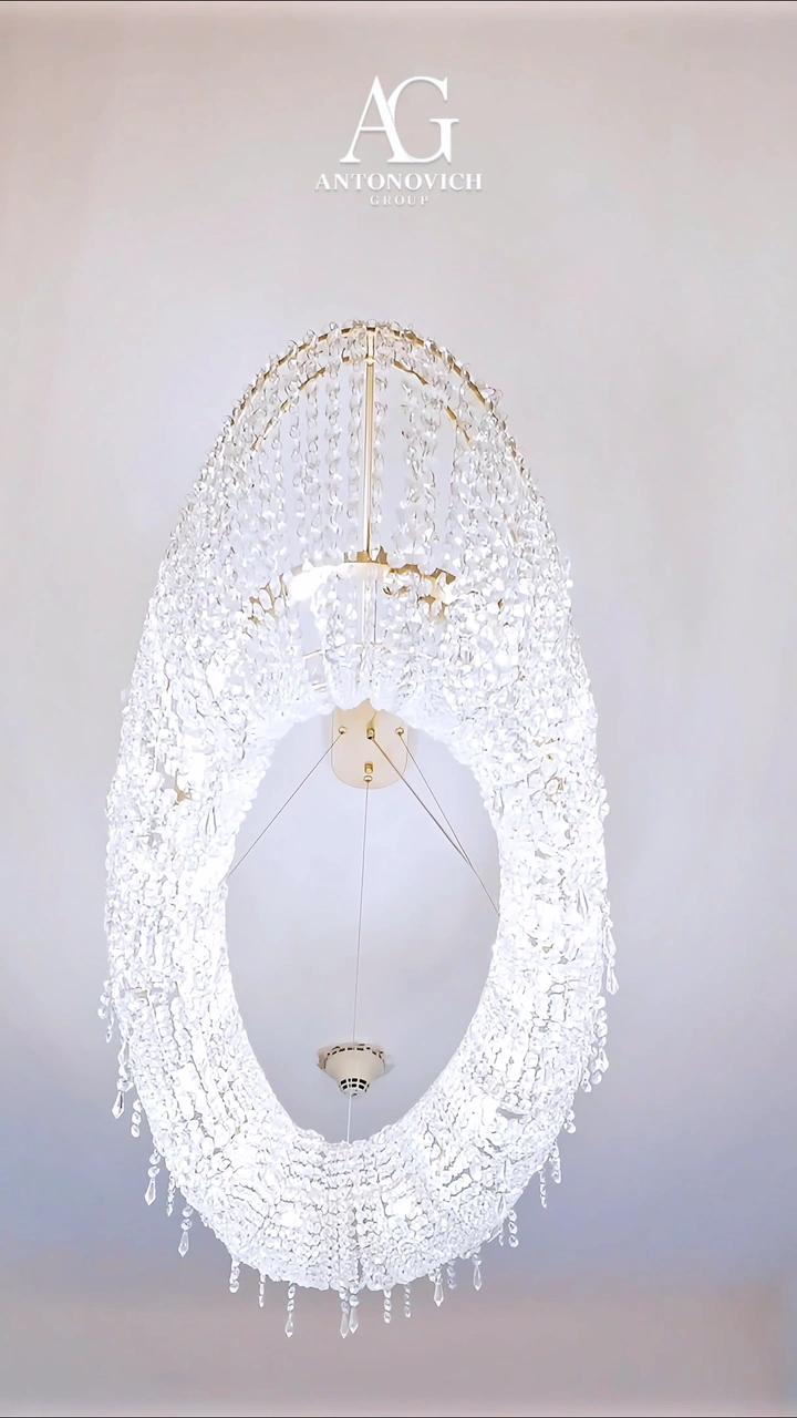 Apartment interior by Antonovich Group with an oval crystal chandelier, fluted cream wall panels, a bedroom with walnut slats and a kitchen with marble counters and bronze bar stools