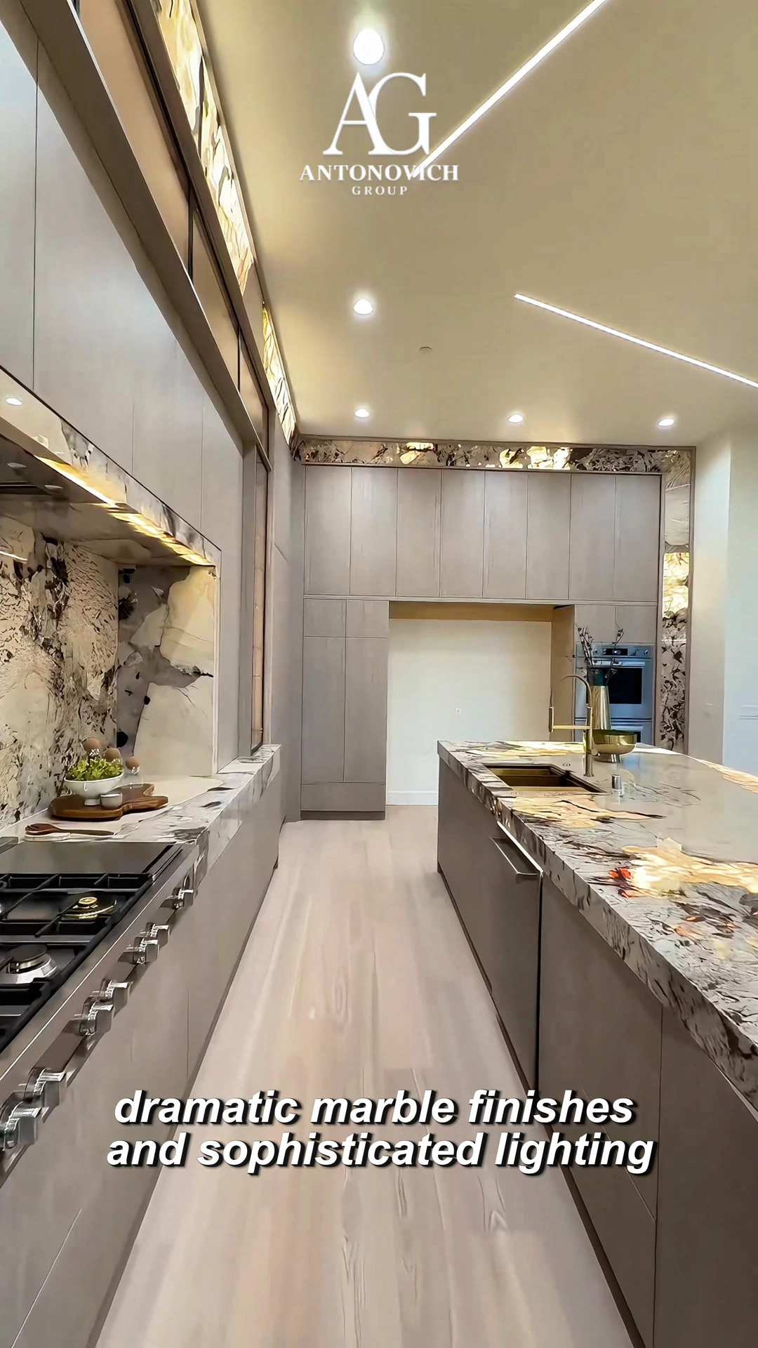 Light luxury kitchen with white gloss and walnut cabinets, a marble dining table and gold pendant lights