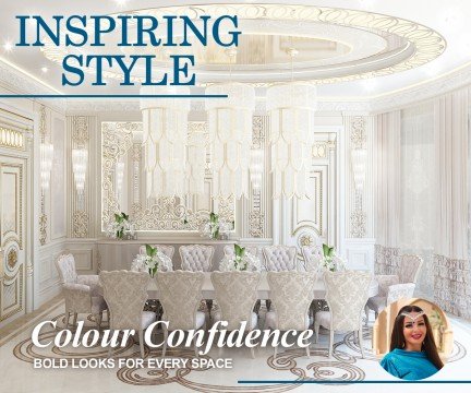 This picture shows a man standing on top of a mountain looking out into a valley. He is wearing warm clothing and standing on a rock that is jutting out from the higher ground. The sunlight is shining through the clouds in the background and illuminating the landscape below him.