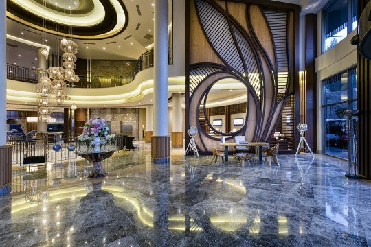 This picture shows a person standing in a narrow alleyway with two large, bright green doors at the end. The walls on either side of the alley are covered in graffiti, and there are several windows at various heights. The person appears to be looking up at the bright green doors, which seem to be their destination.