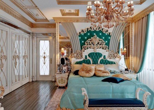 The picture shows a large city skyline with tall buildings and cranes in the background. The sun is setting over the city, making the sky a beautiful shade of orange and pink. In the foreground, a lone figure stands looking out at the view.