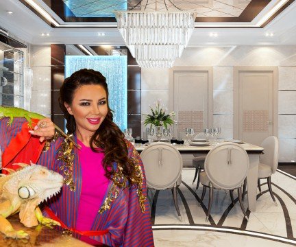 A luxurious living room featuring a curved sectional sofa, large area rug, crystal chandelier, and a modern end table.