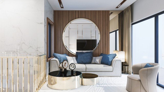 This picture shows a person in their kitchen, preparing food. They are standing at the counter with an array of fresh fruits, vegetables, spices, and other ingredients laid out in front of them. They are holding a wooden spoon in one hand, and appear to be stirring something in a pot on the stove behind them.