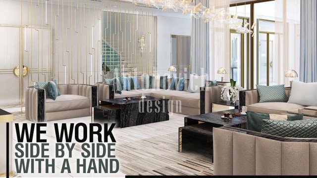 This picture shows a modern, luxurious interior design created by Antonovich Design. It features gold-colored decor accents with black marble flooring and white walls and furniture. There are several sofas with black and gold trim, along with an elaborate seating area that includes multiple armchairs, ottoman stools, and a tall round table. The room is accented by multiple large ornamental plants and tall glass vases filled with flowers.