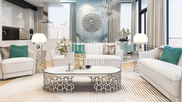 This picture shows an interior design of a modern living room. It includes a large white sectional sofa with a bright red armchair and ottoman as accents. A glass coffee table with a geometric pattern on it sits in the middle. On the walls are abstract art pieces, and a round mirror hangs over the sofa. The flooring is white marble tile and the ceiling features recessed lighting.