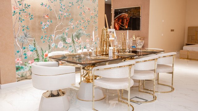 Modern-style living room featuring upholstered sofa, armchair, and ottoman in light hues, accompanied by glass-top coffee table.