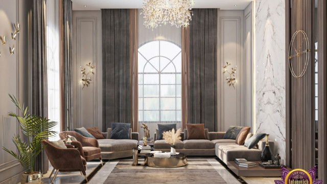 This picture shows a large, modern living room with white walls, light wood floors, and an impressive custom-built ceiling with intricate patterns. The furniture is designed in a modern style, with clean lines, off-white sofas, and contemporary armchairs in bright colors. The large windows and glass doors provide plenty of natural light and offer a relaxing outdoor view. The room is decorated with a few abstract art pieces and a bright yellow accent wall, which adds an interesting color contrast.