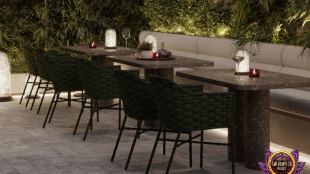 This picture shows an elegantly designed modern living room. The room features a plush white sofa and two armchairs with sleek metal legs that are adorned with geometric pillows. There is a large round coffee table in the center with a lush carpet beneath. The walls are painted a light gray color, and there is a large abstract painting hung on one wall. The overall design of the room is very contemporary and sophisticated.