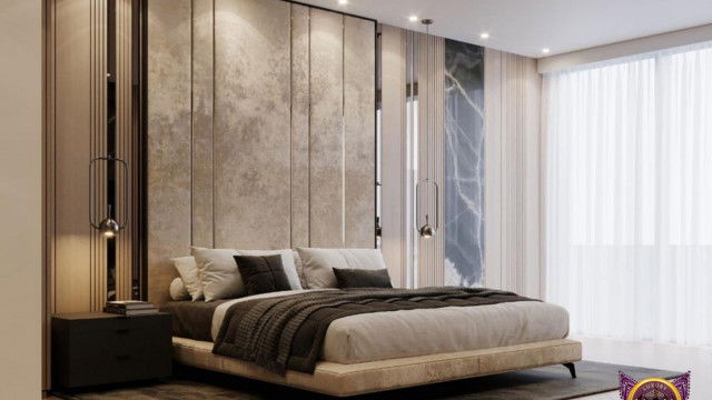 This is a picture of a modern living room with a luxurious design. The main features of the design include an L-shaped white leather sofa, a glass coffee table, two black armchairs, and two floor lamps in the corner of the room. The walls are decorated with a large abstract art piece, as well as several other smaller framed pieces. The floor is covered in a beautiful light wood laminate that extends out to the balcony.