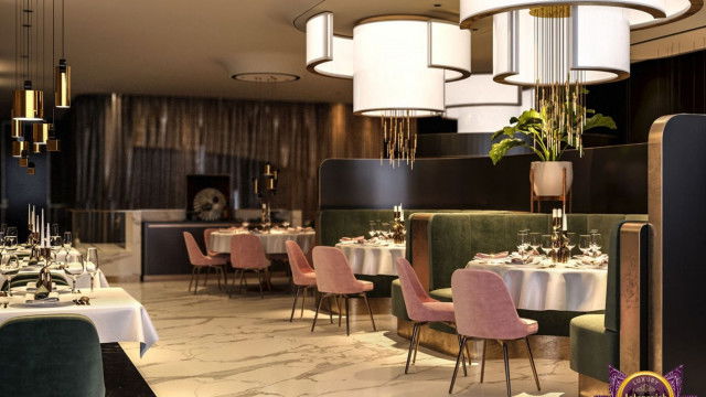 A luxurious and elegantly-furnished living room featuring a grand piano, a fireplace, a pair of armchairs upholstered in a rich emerald hue, and several pieces of art on the walls.