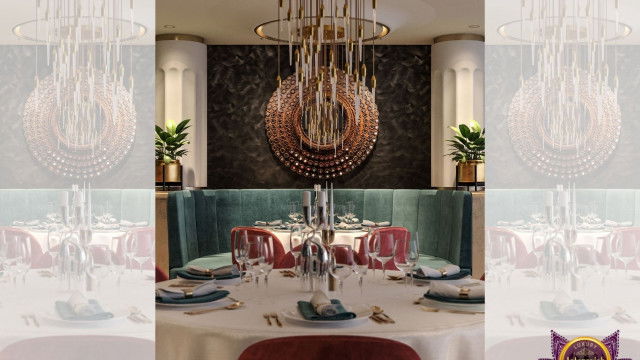 This image shows a modern black and white living room with art deco accents. The floor is a black and white geometric pattern and the walls are painted gray. There is a black leather sofa, two white armchairs, and a small coffee table in the center of the room. The walls are decorated with art deco style light fixtures, and there is a large framed abstract artwork hanging on one wall.