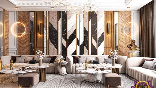 This picture shows a modern, luxury living space designed by Antonovich Design. It features a large, light grey sectional sofa and armchair, facing a striking marble coffee table on a thick white rug. The walls around the furniture are painted in a dark shade of blue with light-colored trim, and accented by an oversized abstract painting and two bronze wall sconces. Behind the furniture is a decorative column and an arched doorway leading to an antechamber.