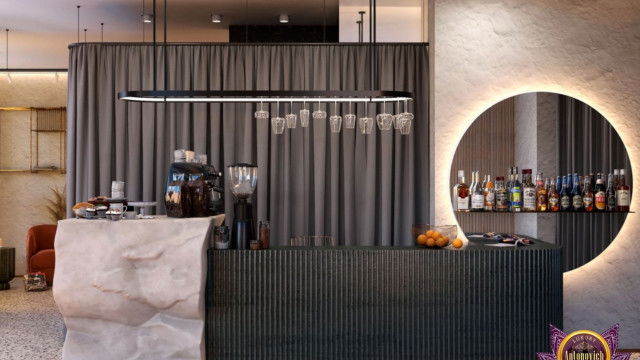 This picture shows a modern, contemporary living room. It has an elegant color palette consisting of beige and gray tones. The walls are painted a light shade of grey, and the furniture is upholstered with a beige fabric. There are two armchairs facing the sofa, and a small coffee table in the center. A white lighting fixture hangs from the ceiling, providing a bright accent to the room. The overall effect is one of sophistication and style.