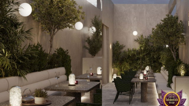 This picture shows a modern living room design with metal furniture and accents. The furniture includes a black metal sofa, white metal chairs and a glass coffee table. A dark grey area rug and matching grey cushions are used to add texture to the space. The walls feature an abstract art piece and a large wall mirror that reflects natural light from the windows. The overall look is minimalistic and sophisticated.