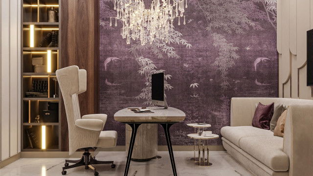 The picture shows a luxurious and modern-style living room with a taupe sofa, cushioned armchairs, ottomans and coffee table. The walls are painted in a light gray color, and there is a large contemporary fireplace with a black marble surround and wood mantel. A round, white chandelier hangs above the coffee table, and there are various plants and artwork throughout the space.