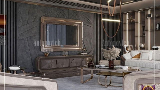 This picture shows a luxurious white and gold bedroom with ornate details. It features a white headboard, bed frame, and night stands with golden accents. A white chandelier hangs above the bed, and there is a large mirror with a golden frame on the wall. The walls are painted in a pale green color, and the floor has a cream-colored rug.