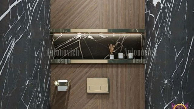 This picture shows a luxurious living room with a striking beige and brown color palette. The room features an elegant cream-colored sofa with two matching armchairs arranged around a glass-top coffee table. There is an ornately framed mirror above the couch and a pair of large windows on the right, letting in plenty of natural light. On the left side of the room, there is a grand fireplace with a mantelpiece decorated with a golden vase and candles. A round area rug in hues of chocolate and tan adorns the floor, while the walls are decorated with several pieces