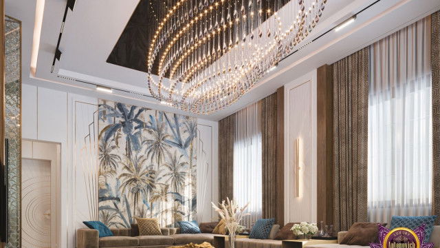 Modern, luxurious living room with white and light beige walls, white ceiling, round shaped light fixture, large sectional sofa upholstered in light beige fabric, two end tables with tall lamps, and brown and gold area rug.