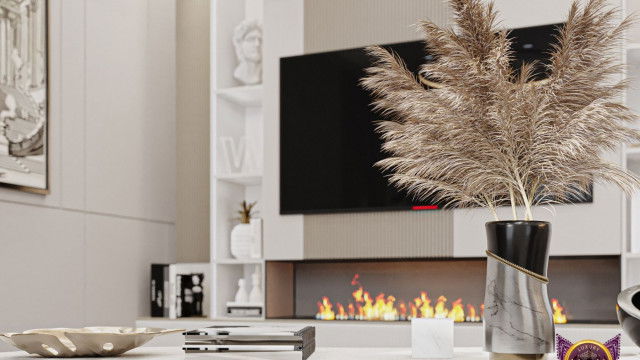 This picture shows a luxurious modern living room designed by Antonovich Design. The room is decorated with gold accents, such as the gold-framed artwork and golden pillows. There is an abundance of plush seating in the room with accent chairs and a velvet sofa. The walls are covered with a soft white wallpaper with a subtle pattern, and there is a light brown area rug to give the room some added warmth.