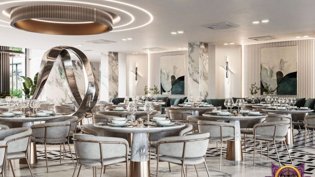 This picture shows an interior design of a modern bedroom. It appears to be a contemporary and luxurious space with its hardwood floors, high ceilings, and white walls that contrast with the dark furniture and bold accessories. The focal point of the room is the statement bed which is encased in a beautiful canopy and accompanied by a tufted chaise lounge. On either side of the bed are distressed nightstands, adding to the decor. Discreet lighting fixtures complete the look of the space.