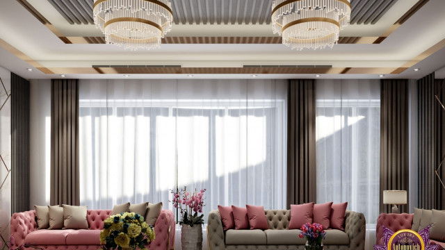 This picture shows a luxurious kitchen with a large marble countertop set against a sleek dark grey cabinet. The kitchen features modern, stainless steel appliances including a range hood, an oven, and a built-in refrigerator. There is also an island with a white countertop and multiple cabinets underneath, providing ample storage space. The room is illuminated by recessed lighting and a unique pendant light hanging from the ceiling.