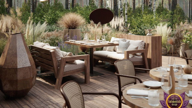 This picture shows an ornate and luxurious living room. It features a velvet sofa with a coral colored accent wall, several ornate mirrors hung on the walls, and various other pieces of furniture such as a coffee table, chairs, and side tables. On the left side of the image, there is a grand chandelier hanging from the ceiling, adding to the overall lavish feel of the room.