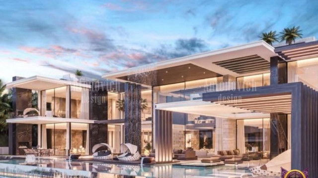 This picture appears to show a contemporary living room with light wood floors and a white ceiling. The walls are painted a soft grey, and the main focus of the room is a white L-shaped sectional sofa with accent pillows in shades of blue and grey. On either side of the sofa are modern white coffee tables with tall metal legs. On one side there is a decorative hearth with white and grey stones and a large metal candle holder. There is also a black media console with two large speakers and a wall-mounted television. The overall design of the room is very modern and