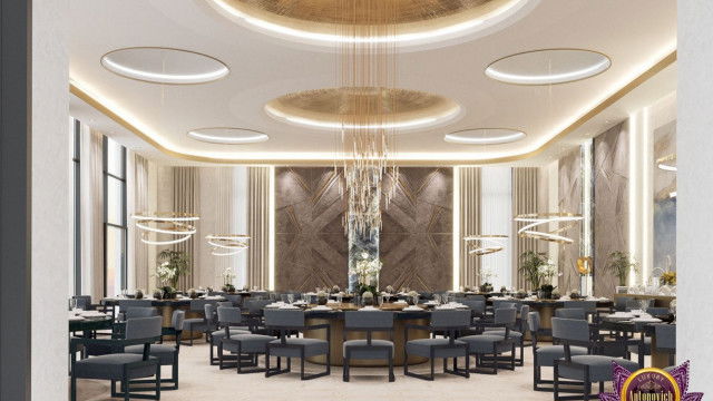 This picture shows a luxury living room with a dark brown and white color scheme. The room has a seating area with a white sofa and two armchairs upholstered in chocolate-colored velvet. On the other side of the room, there is a wall with built-in shelving and a flat screen TV mounted on it. The floors are covered in parquet wood in a herringbone pattern. The walls have large built-in window frames and several wall lamps with intricate golden details. A small glass round table with a golden base is placed in one corner with a statement rug