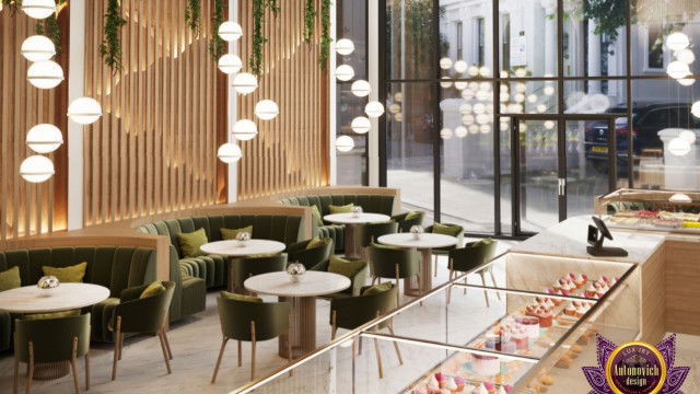 This picture shows a large, luxurious master bedroom with a canopy bed. The walls are a light blue and decorated with light yellow curtains above the bed. There is a dark grey bedspread with white and beige pillows and a tall wooden nightstand next to the bed. On the other side of the room is a white armchair and a long white shelf with decorative pieces of art. The floor is carpeted in a light beige hue and several modern light fixtures hang from the ceiling.