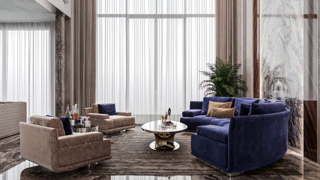 A contemporary living room featuring a soft, off-white sofa complemented by armchairs upholstered in a mustard yellow fabric. The coffee table is crafted from dark, polished wood, and stands across from a large flat-screen television mounted on the wall.