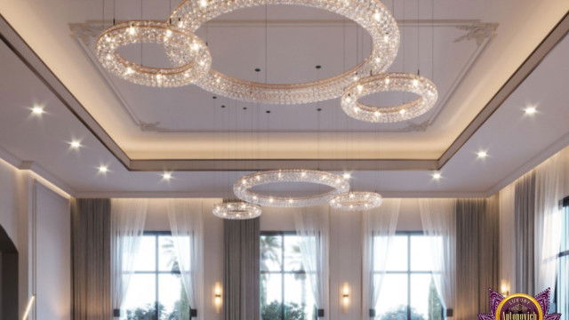 This picture shows what appears to be a modernized living room, complete with a comfortable and stylish sofa, an armchair and ottoman, a pair of pendant lights, and a wall-mounted television. The room is decorated with various accents and interesting wall art, as well as a patterned rug, and hints at the modern and elegant aesthetic that can be achieved through thoughtful design.