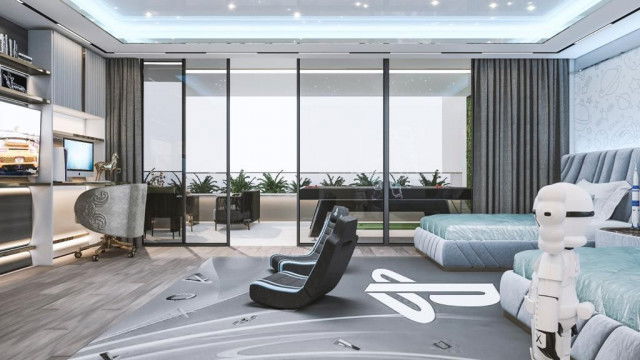 This picture is of a modern kitchen with dark, glossy cabinets and counters, as well as white marble countertops. The room features stainless steel appliances, a large kitchen island with four tall chairs, an eat-in dining area with two comfortable chairs and a glass-top table, and a large window with a sheer curtain. There are also multiple pendant lights hanging above the island and the dining area.