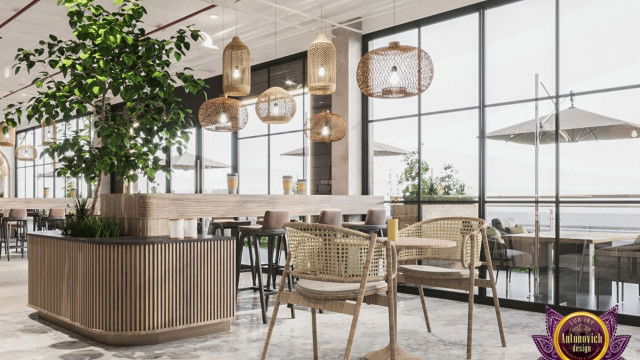 This picture shows a modern living room with an open-concept design. The room features a large white sectional sofa, two armchairs, and a large ottoman that serves as both a footrest and coffee table. A sleek gas fireplace is centered in the wall, and a glass wall separates the living room from an outdoor patio. The walls are painted a light gray color, while the furniture and accents provide pops of color, making the space warm and inviting.