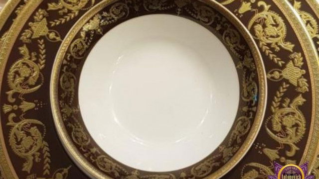 Modern interior design featuring an ornate white and grey color palette, with a marble floor, moldings, and a curved staircase.