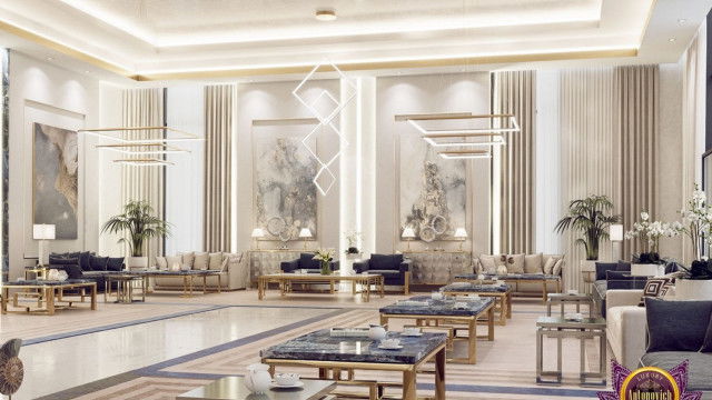 Modern interior featuring white-walled space filled with expensive furniture, including a large gray chaise lounge, glass-top table, and white sofa with decorative patterned pillows.