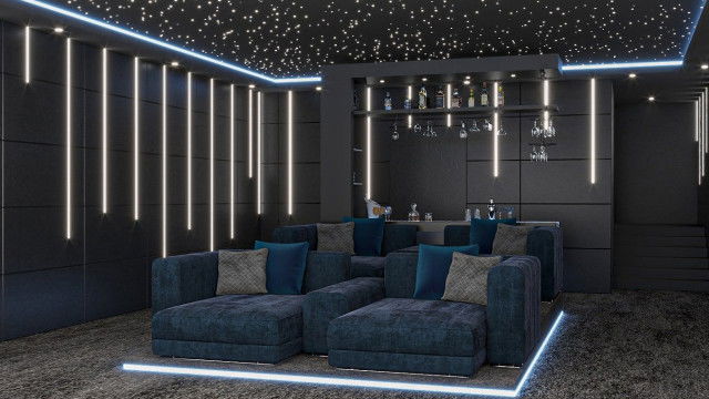 This picture is of a modern bedroom designed by Antonovich Design. The room features a pale pink accent wall, tan-colored carpeting, and modern white furniture. A large window in the center of the wall allows natural light to flow into the room. A closet can be seen to the left side of the room, as well as a dresser directly across from it. On the right side of the room there is a bed with a tufted headboard and gold accents. In addition, there is a bedside table with a vase on top. Overall, the design is