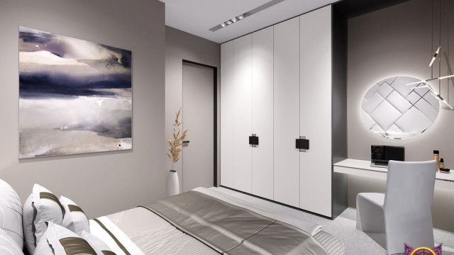 This picture shows a modern living room with an open floor plan. The space includes a grey sectional sofa and a matching ottoman placed in front of a gas fireplace. A wooden console table is situated beneath a flat-screen TV, while a rattan pendant light illuminates the center of the room. Natural wood finishes can be seen on the coffee table, side tables, and built-in shelving.