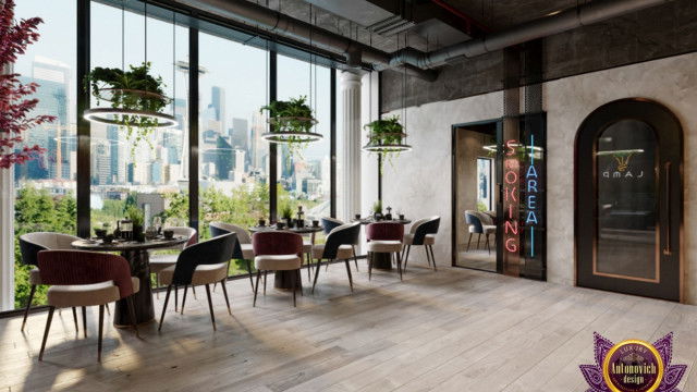 This picture shows a luxurious, contemporary living room. It features plush white couches with colorful accent pillows. The room includes a fireplace, a large jade green area rug, white shaggy chairs, and a glass and steel coffee table. There are floor-to-ceiling windows that provide an abundance of natural light, and an interesting piece of artwork hangs on the wall above the mantel.