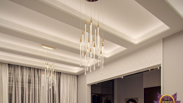 The picture shows an interior design with a large white sofa in the center of the room. The walls are painted gray and there is a curved wall separating the living area from the dining area. The living area has two armchairs and several potted plants, while the dining area has a round dining table with six chairs placed around it. The floor is covered in a parquet pattern, while the ceiling has several exposed wooden beams.