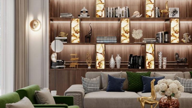 This picture shows a modern living room design with a beige colored sofa and accent chairs, a glass coffee table, and a white rug in the center of the room. There are also two modern sculptures on either side of the sofa, as well as decorative shelves and wall art on the walls. The overall design is accented with indirect lighting for a warm, inviting atmosphere.