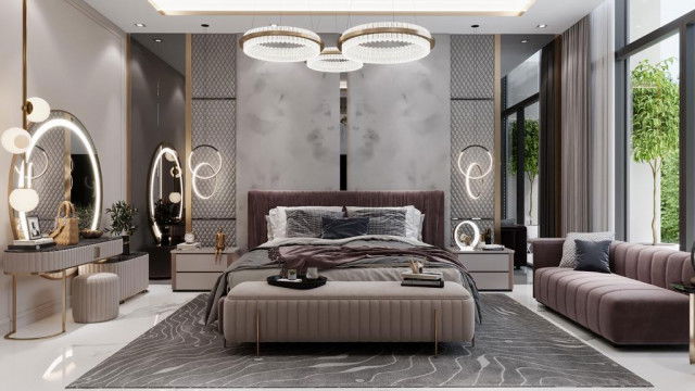 This picture is of a luxury living room designed by Antonovich Design. It features a large, traditional style sofa upholstered in a rich, classic pattern and a matching ottoman. The walls are decorated with an extravagant gold mirror, ornate framed artwork, and black and white accents. A elegant white ceramic table lamp and a modern glass chandelier add accents of sparkle and sophistication to complete the look.