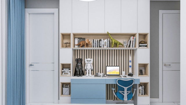 The picture shows a modern, luxurious living room with a white marble fireplace, surrounded by abstract artwork, and simple furniture upholstered in gray velvet. The walls are painted a creamy white, while the ceiling is adorned with intricate moldings. The room is illuminated by both natural light coming in through the large wall-to-wall windows and modern lighting fixtures.