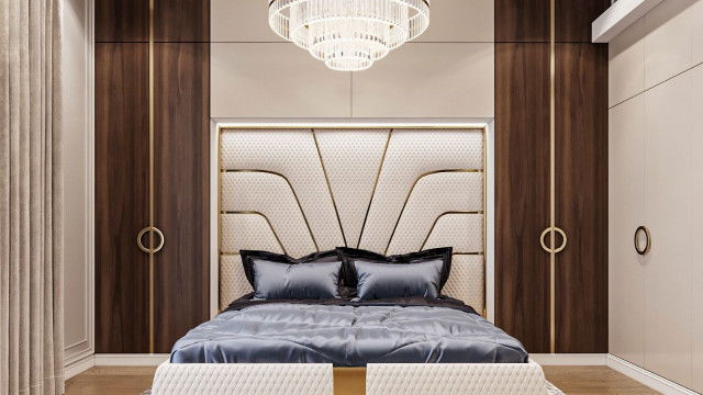 This is a picture of a modern living room with an opulent, luxurious design aesthetic. The room features hardwood flooring with an area rug and a plush velvet sofa, coffee table, and armchair upholstered in luxurious fabrics. There is also a sleek metal fireplace and two floor lamps to provide additional light and atmosphere. The walls are adorned with several gold-framed art pieces and there are tall windows that look out onto a scenic landscape.