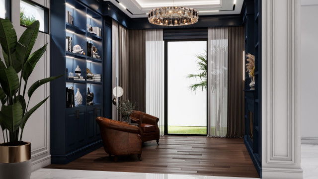 This picture shows an elegant, modern living room featuring a round couch, two armchairs around a small round ottoman in a light blue color. The walls are covered with a luxurious wall covering in a soft gray pattern and the floor is grey tile. The room has a large, ornately framed mirror on one wall, and several abstract paintings on the other walls. There is an arc-shaped floor lamp near the couch, as well as several decorative plants around the room.