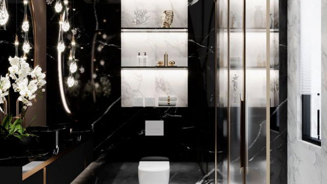 This picture shows a luxurious modern living room with a comfortable elegant sofa and armchair, set in front of a statement wall with a recessed fireplace. The black marble floor and walls are complemented by the grey furniture upholstery and white panel walls, creating a chic and sophisticated atmosphere. There is a coffee table and sideboard in the corner, as well as artwork and decorative accessories, bringing the whole look together.