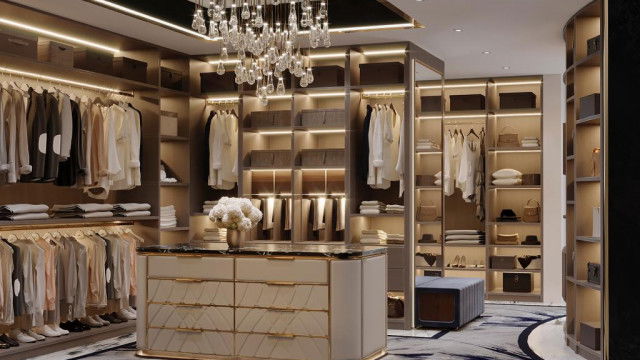 This picture shows a luxurious modern kitchen design with a large central island featuring a built-in sink and cooktop. The kitchen also features a large marble backsplash, wooden cabinets, and modern appliances. The flooring is composed of a light-colored porcelain tile, and the walls are painted in a neutral cream color. The overall design of the room creates a sleek and elegant atmosphere.