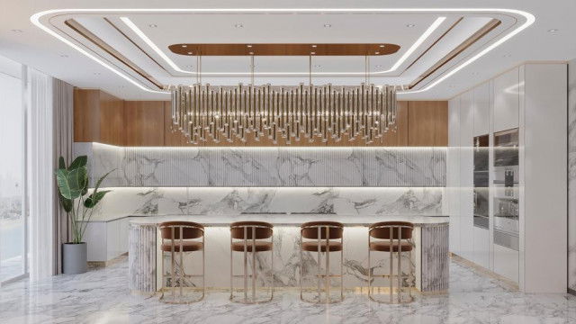 This picture shows a modern kitchen design featuring a large island and countertops made of white quartz, illuminated with white LED lighting. The cabinets are in a two-tone color with the lower units in a bright teal shade and the upper units in white. A kitchen range is located on the Island surrounded by stylish bar stools. The island has ample storage space, deep drawers, and wine racks. The floors are covered in checkered tile which adds a stylish contrast to the overall design.