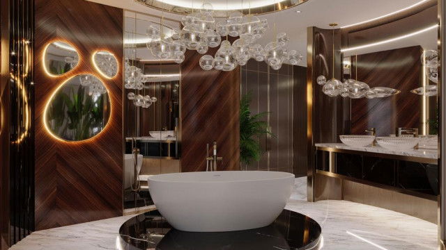 The picture shows an interior design project by Antonovich Design. It is an ornately decorated living space featuring a luxurious gray sofa, a coffee table surrounded by gold and white armchairs, and an elaborate wall art design with a large round mirror in the center. The walls are painted white and decorated with gold accents, while the floor is crafted with wood tiles. The design is finished with a large chandelier to give the room an elegant atmosphere.