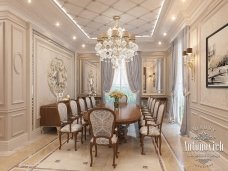 The picture shows a young woman with dark hair and a beard, wearing a light pink t-shirt, white shorts and colorful sneakers, standing in the middle of a grassy field with tall trees in the background. There is also a kite in the background, with some blue and pink colors.